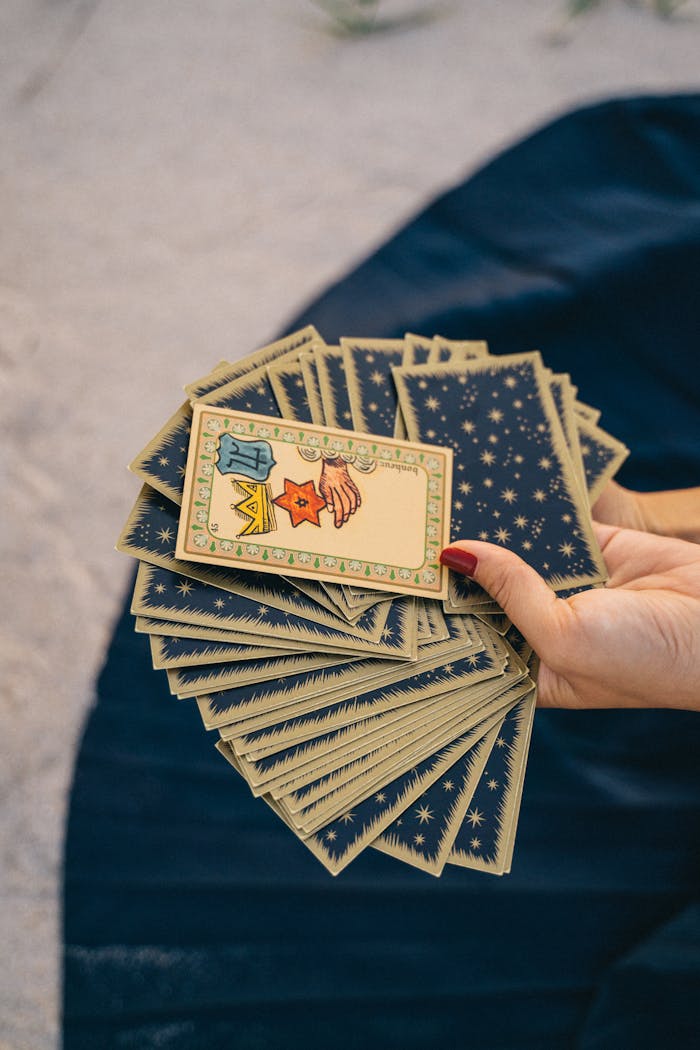 A hand holding a deck of tarot cards, symbolizing spirituality and divination.